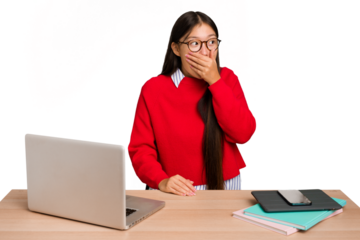 Young student asian woman in a workplace with a laptop isolated thoughtful looking to a copy space covering mouth with hand.
