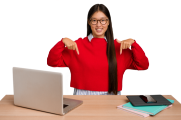 Young student asian woman in a workplace with a laptop isolated points down with fingers, positive feeling.