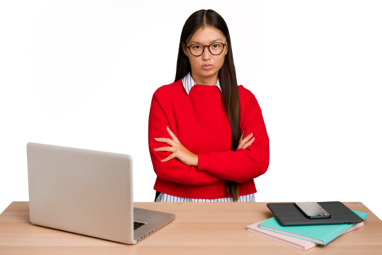 Young student asian woman in a workplace with a laptop isolated frowning face in displeasure, keeps arms folded.