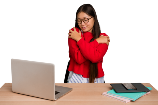 Young student asian woman in a workplace with a laptop isolated hugs, smiling carefree and happy.