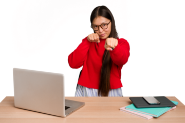 Young student asian woman in a workplace with a laptop isolated throwing a punch, anger, fighting due to an argument, boxing.
