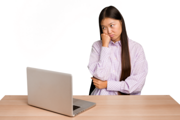 Young student asian woman in a workplace with a laptop isolated who feels sad and pensive, looking at copy space.