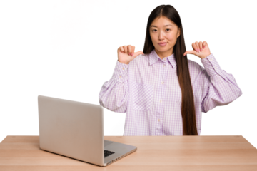 Young student asian woman in a workplace with a laptop isolated feels proud and self confident, example to follow.