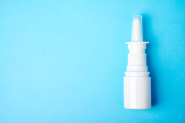 Nasal spray bottle on blue background with copy space