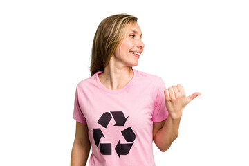 Young caucasian woman wearing a recycling t-shirt isolated points with thumb finger away, laughing and carefree.