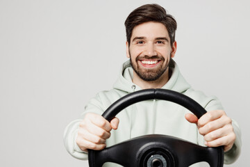 Young smiling happy fun satisfied cheerful caucasian man wear mint hoody look camera hold steering wheel driving car isolated on plain solid white background studio portrait. People lifestyle concept. - Powered by Adobe