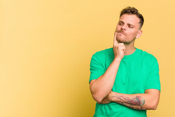 Young caucasian handsome man isolated on yellow background looking sideways with doubtful and skeptical expression.