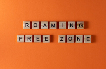 Roaming free zone word phrase in wooden letters. Motivation and slogan. Orange background.
