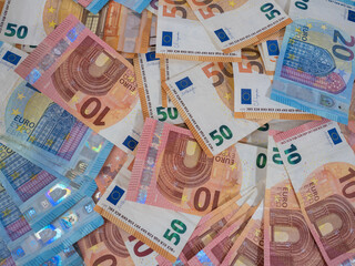pile of ten, twenty and fifty euro bills spread out on a table. foreground. top view. inflaction