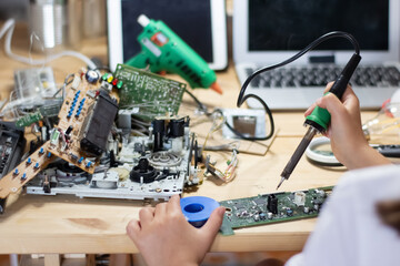 Close-up of pupils hands assembling circuit board on desk at lab. School girl learning electronic circuit. Education, hobby, robotics, technology concept