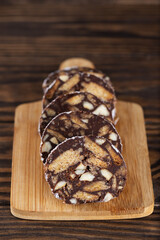 Sliced chocolate sausage salami on a wooden board, without sugar, gluten and lactose.