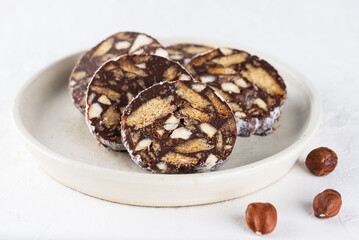 Vegan chocolate sausage salami with hazelnut on plate without sugar, gluten and lactose.
