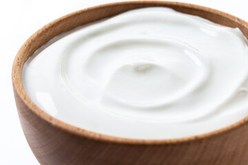 Greek yogurt in wooden bowl isolated on white background. Creamy natural yogurt