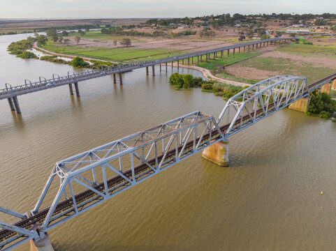 Aerial view of a steel bridge crossing a wide brown river