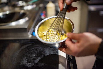 man chef cooking tasty scrambled eggs on kitchen
