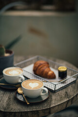 Fototapeta na wymiar Two cups of cappuccino and fresh croissant with jam on wooden table.