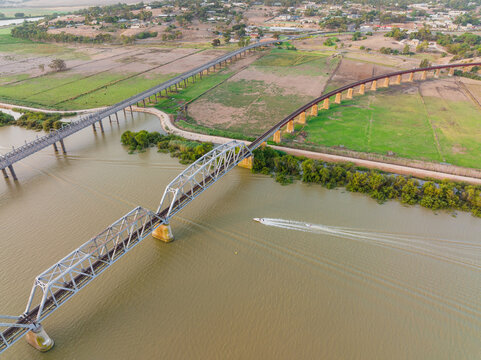 Aerial view of bridges crossing a wide brown river alongside farmland