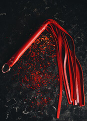 bdsm toys, red leather whip on a black background with red glitter