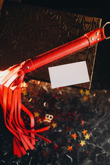 card mockup, mockup of a white sheet of paper bdsm toys, red leather whip on a black background...