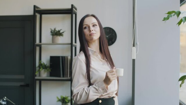 young business woman standing in the office and drinking coffee