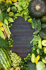 vegetables and fruits in green and yellow colors with a place for writing in the center on a wooden background.