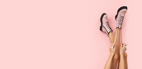 Fashionable pink boots on slim woman legs on pastel pink background with free place for text.
