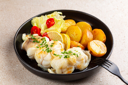 Fried monkfish with butter, parsley and garlic, also called fishing-frogs, frog-fish, and sea-devil. Baked baby potato and salad. Healthy fresh seafood dish.