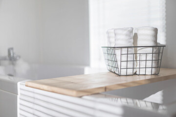 Fototapeta na wymiar White bath towels rolled in metallic basket on wooden shelf bathroom arrangement storage top view