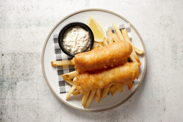 top view shot of fish and chips with buttermilk ranch dipping sauce all placed in a white plate