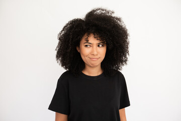 Confused woman showing doubt. Hispanic female model with afro hairstyle and brown eyes in casual...