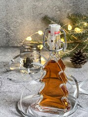 Christmas liqueur with spices. It goes perfectly with gingerbread. A bottle in the form of a Christmas tree. Decorative cup with the image of a deer and table decoration.