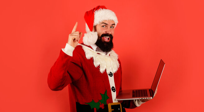 Santa Claus shopping online with laptop. Buying christmas gifts. Bearded man pointing finger up.
