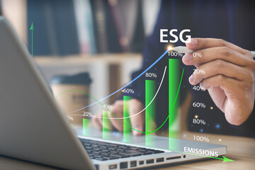Businessman pointing at the word ESG with a pen on a computer screen  with green graph  In the upward trend of socially responsible business