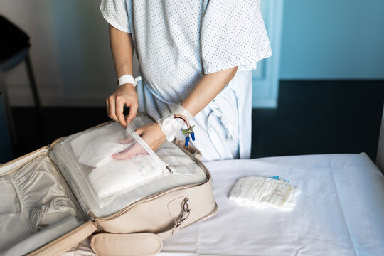 woman who has just given birth in the hospital picks up the suitcase with her things and those of her newborn baby to go home when she is discharged