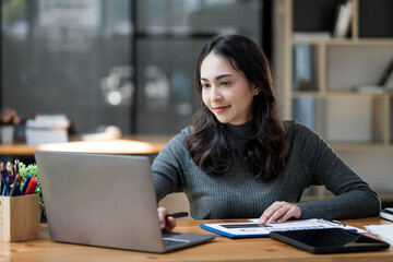 Portrait of Young asian indian Businesswoman Sitting at Her Desk Working on Laptop Computer.