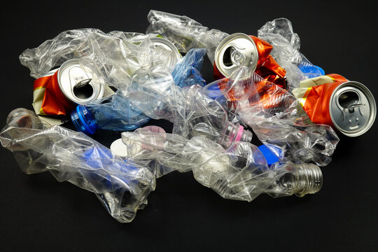 Crumpled plastic bottles and aluminum canson a black background