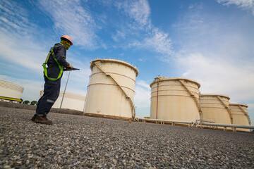 Obraz premium Male worker works permit industry visual inspection the row of big white tanks for petrol station