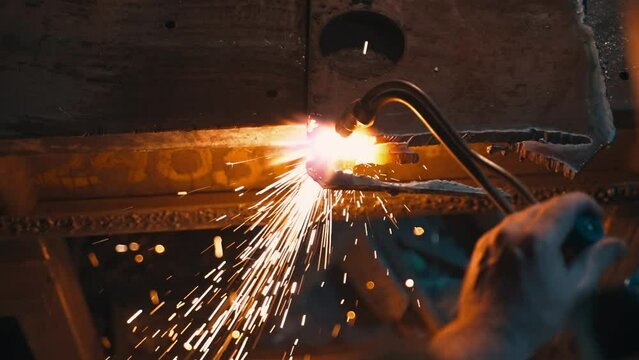 An industrial worker cuts steel with an oxygen torch.