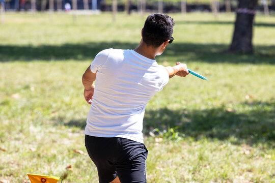 Disc golf player throwing a flying disc sport game in the park or nature