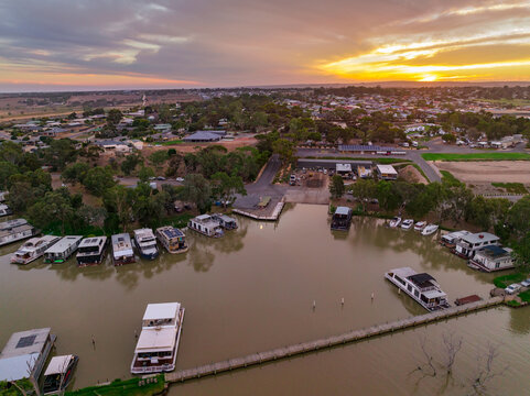 Aerial view of a house boat marina on a river with a sunset behind
