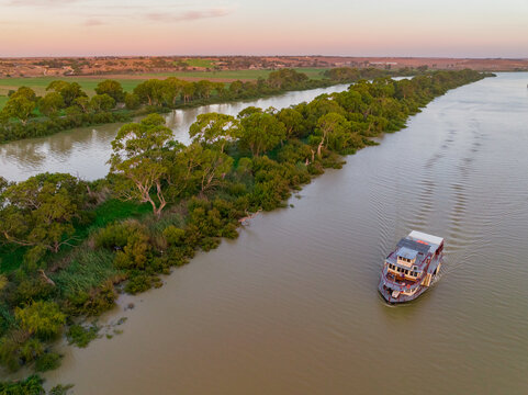 Aerial view of a paddle steamer on a wide brown river at twilight