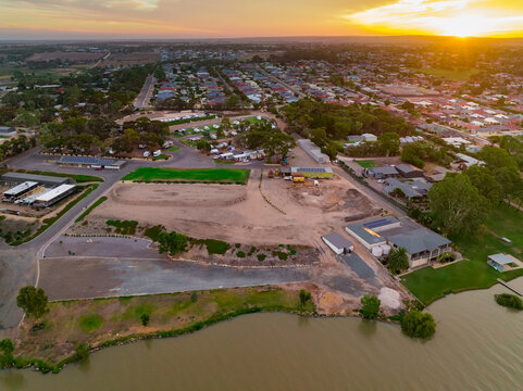 Aerial view of a construction site on the bank of a wide brown river at sunset