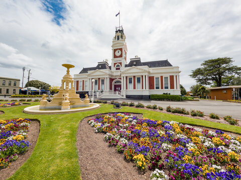 Colourful garden beds and a fountain in front of an historic Town Hall with a clock tower