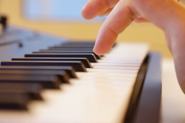 Keyboard keys close up. Right hand is going to play a note. Professional equipment for studio production. Music production and performance concept.
