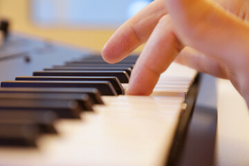 Fototapeta na wymiar Keyboard keys close up. Right hand finger playing a note in focus. Professional equipment for studio production and live performances. Music production and performance concept.