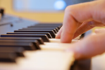 Fototapeta na wymiar Keyboard keys close up. Right hand is playing a four note chord. Professional equipment for studio production and live performances. Music production and performance concept. 