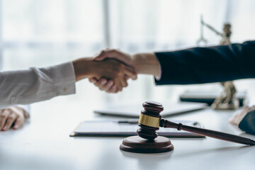 Lawyer shaking hands with client after agreement Gavel Justice hammer on wooden table with judge and client shaking hands after advice in courtroom, notary service concept