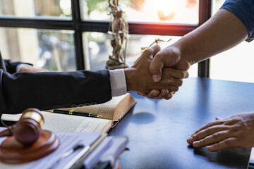 Lawyer shaking hands with client after agreement Gavel Justice hammer on wooden table with judge and client shaking hands after advice in courtroom, notary service concept