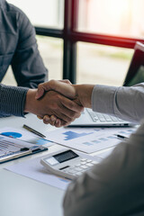 Businessmen shaking hands with clients in modern conference room The team leader meets the group to greet each other. Handshake showing trust and respect, financial concept  
 vertical image