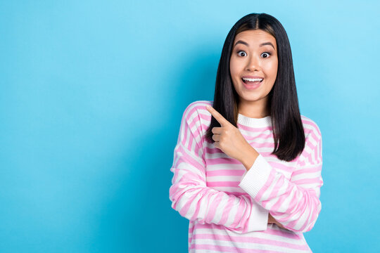 Photo of cheerful impressed young girl dressed pink pullover pointing finger empty space smiling isolated blue color background